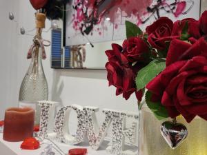 un jarrón lleno de rosas rojas sentadas en una mesa en Prosecco Palace, en York