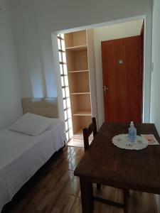 Un dormitorio con una cama y una mesa con una botella de agua. en POUSADA ELMIRA´S BELA VISTA, en Ouro Branco
