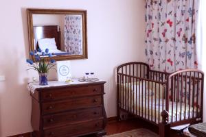 a bedroom with two cribs and a dresser and a mirror at Casa Charmosa in Funchal