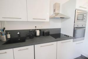 a white kitchen with a sink and a microwave at Vieux Lille: bright, functional apartment in Lille