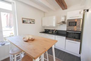 リールにあるVieux Lille: bright, functional apartmentの白いキャビネットと木製テーブル付きのキッチン