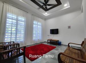 uma sala de estar com um tapete vermelho e uma televisão em Gemia Rumah Tamu - 3 bilik aircond - near nasi dagang Atas tol 