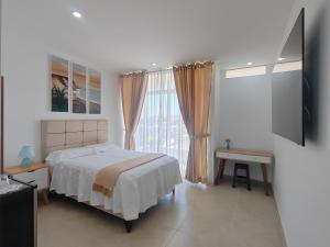 a white bedroom with a bed and a window at La Terraza Suite Chicama in Puerto Chicama
