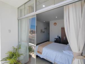a bedroom with a bed and a glass wall at La Terraza Suite Chicama in Puerto Chicama