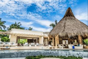 a villa with a pool and a thatch roof at Hidden All inclusive House in Punta Mita in Punta Mita