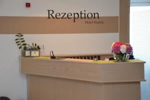 a reception counter with flowers in a vase on it at Hotel Hamm in Weiterstadt