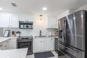 una cucina con mobili bianchi e un frigorifero in acciaio inossidabile di Phoenix X 1403 condo a Orange Beach