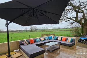 ein schwarzer Regenschirm über einer Couch mit Kissen und einem Tisch in der Unterkunft Le Petit Loup grande maison de charme en campagne in LʼOie + 59 Fotos