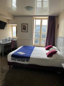 a bedroom with a bed and a desk and a window at Cit'Hotel le Challonge in Dinan