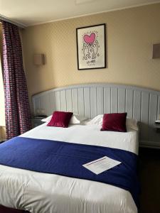 a bedroom with a large bed with two red pillows at Cit'Hotel le Challonge in Dinan