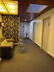un pasillo con sofá y una pared de flores en Cit'Hotel le Challonge en Dinan