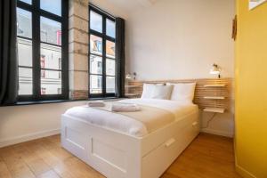 białe łóżko w pokoju z oknami w obiekcie Unique 3 bed house in Old Lille! w Lille