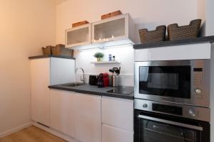 kuchnia z białymi szafkami i mikrofalówką w obiekcie Unique 3 bed house in Old Lille! w Lille