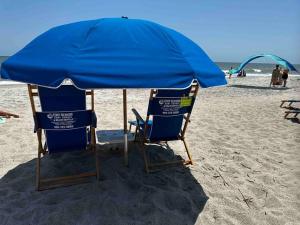 dos sillas bajo una sombrilla en una playa en Beachfront-Boardwalk-Elevator-Pool-Free Parking for 2 Cars! en Carolina Beach