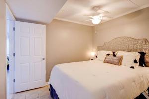 1 dormitorio con 1 cama blanca y ventilador de techo en Beachfront-Boardwalk-Elevator-Pool-Free Parking for 2 Cars! en Carolina Beach