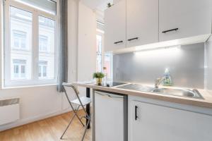 cocina con armarios blancos, fregadero y ventana en Lille Saint Maurice - Nice and functional studio, en Lille