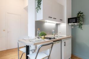 una cocina con armarios blancos y una mesa con sillas. en Lille Saint Maurice - Nice and functional studio en Lille