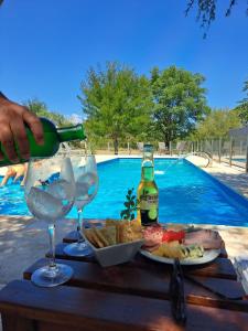 a person pouring a bottle of wine into two glasses at Casas Acrux in Nono