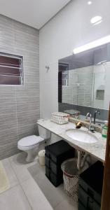 ein Badezimmer mit einem WC, einem Waschbecken und einem Spiegel in der Unterkunft Casa 3 dorm, prox a 2 praias e da Riviera tb. in Bertioga