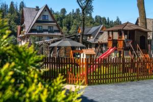 a fence with a playground in front of a house at Apartament Pod Tatrami in Biały Dunajec