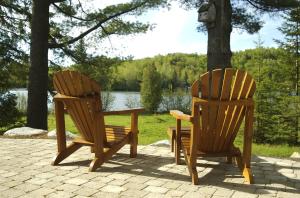 2 sillas de madera y una mesa frente a un lago en Les Chalets du Lac Grenier, en Chertsey