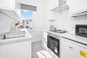 cocina blanca con fregadero y fogones en Fabulous Apartment Overlooking Canal - Parking - Perry Barr - WIFI - Netflix - 3PB, en Birmingham