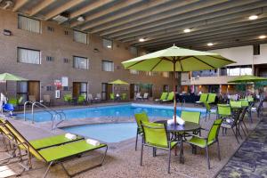 uma piscina do hotel com cadeiras, mesas e guarda-sóis em Best Western Plus Kelly Inn em Saint Cloud