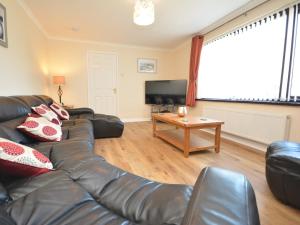 a living room with a leather couch and a tv at 5 bed in Brynteg 75907 in Llanwenog
