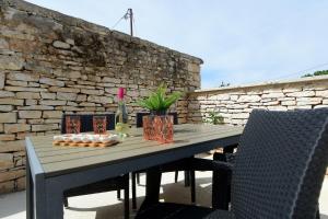 a wooden table with a bottle of wine on a stone wall at Apartman Paštura in Vodnjan