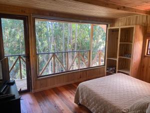 ein Schlafzimmer mit einem Bett und einem großen Fenster in der Unterkunft Refugio Nomade Apartamentos in Pichilemu