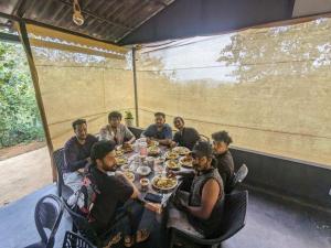 un grupo de personas sentadas alrededor de una mesa comiendo comida en Spirit of the Wild Retreat @ IMark Valley, en Attappādi