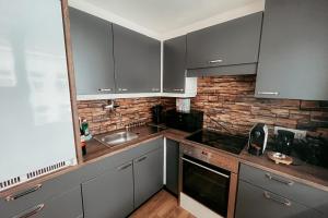 a kitchen with gray cabinets and a brick wall at Vienna Stadthalle Apartment 19 in Vienna