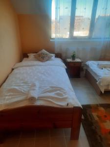 1 dormitorio con 1 cama con sábanas blancas y ventana en La mama Emilia en Recaş