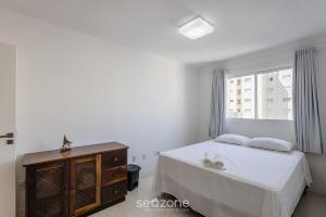 een witte slaapkamer met een bed en een raam bij Amplo apto a 4 min da praia em Itapema/SC DBC0701 in Itapema
