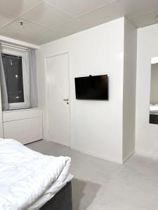 a white bedroom with a bed and a flat screen tv at Nomad Gardet in Stockholm