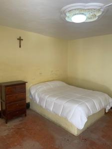 a bedroom with a bed and a cross on the wall at Hostal Las Quince Letras in Tehuacán