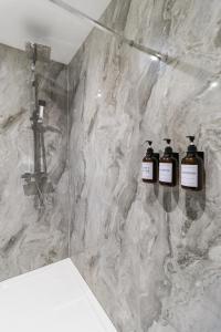 a bathroom with three bottles of soap on a marble wall at WhiskAwayStays - Victoria House - Apartment 5 in Worcester +24 photos