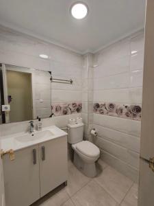 a white bathroom with a toilet and a sink at Beach and sun guest house in Torrevieja