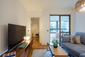 uma sala de estar com um sofá e uma televisão em Coqueto apartamento, céntrico, con garaje y piscina by Prishomes em Vigo