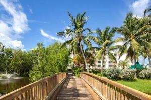 基韋斯特的住宿－The Trinidad by Brightwild-Pool & Parking，一座棕榈树和建筑的河流上的桥梁