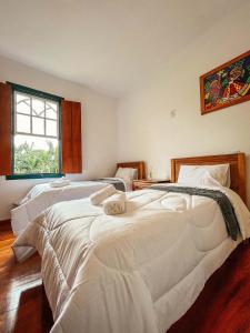 a bedroom with two beds and a window at Pousada do Gentil in Tiradentes