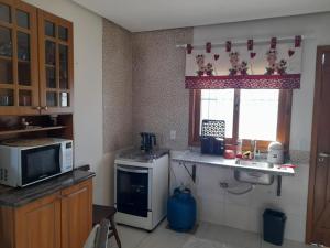 a kitchen with a microwave and a stove and a window at Duplex novo in Tramandaí