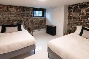 1 dormitorio con 2 camas y pared de ladrillo en The Old New // Spacious 2000 sqft condo - Downtown en Quebec