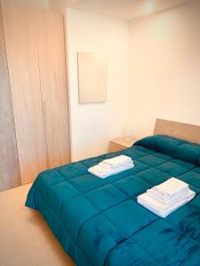 a bedroom with a blue bed with towels on it at Villa MarGiù holidays in Sciacca