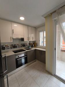 a kitchen with white cabinets and a stove top oven at Beach and sun guest house in Torrevieja