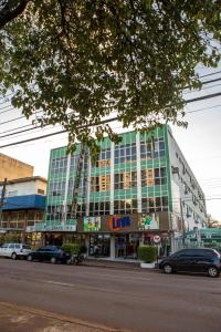 Un grand bâtiment avec des voitures garées devant lui dans l'établissement Grand Prix Hotel, à Cascavel