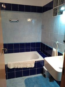 uma casa de banho em azulejos azuis com uma banheira e um lavatório em Casa rural El Majuelo em Portera