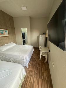 ein Hotelzimmer mit 2 Betten und einem Flachbild-TV in der Unterkunft Pousada da Celma in Fortaleza