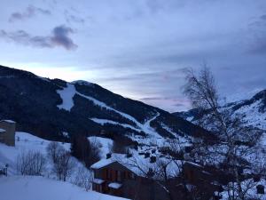 einen schneebedeckten Berg mit einem Haus im Vordergrund in der Unterkunft APARTAMENt MAIANS in Soldeu