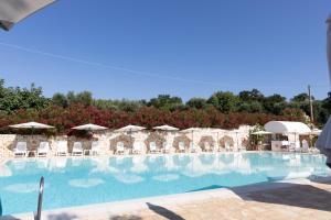 a large swimming pool with chairs and umbrellas at Residenza Aurora in Ostuni